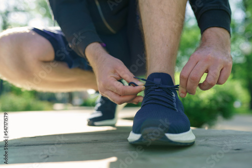 Closeup of young man runner tying her shoelaces. Selective focus