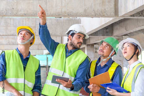 l.Young Middle Eastern engineer at construction site inspect construction with Asia team. Skilled professional work experience. Multi-ethnic civil engineering group unite cooperate same goal.