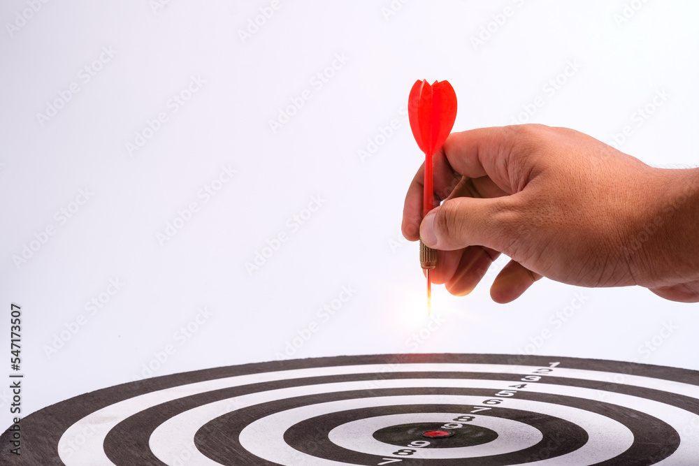 Hand holding dart arrow hit in target center of dartboard, successful business concept. Executive marketing, investment goal and target for business investment concept. Hand holding dart arrow hit in target center of dartboard, successful business concept. Executive marketing, investment goal and target for business investment concept.