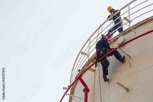 Male worker rope access industrial working at height tank oil wearing harness, helmet safety equipment rope access inspection of thickness tank
