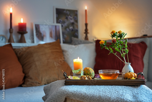 Relaxation with tea, candles and autumn decoration on a tablet in front of the couch in the cozy living room, copy space, selected focus