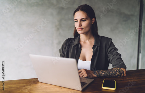 Serious woman working on laptop at workplace