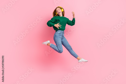 Full length photo of cheerful excited girl dressed knitted pullover enjoying songs play guitar jumping isolated pink color background © deagreez