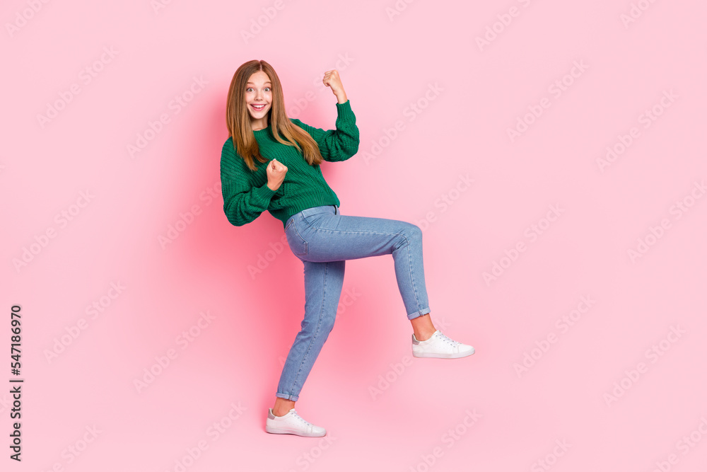 Full length photo of cheerful lucky girl dressed knitted pullover rising fists empty space isolated pink color background Full length photo of cheerful lucky girl dressed knitted pullover rising fists empty space isolated pink color background
