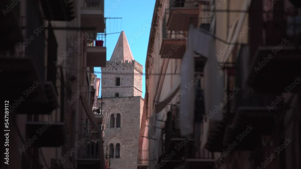 View of one of the Cefalù Cathedral towers at the end of a narrow street in Sicily, Italy View of one of the Cefalù Cathedral towers at the end of a narrow street in Sicily, Italy