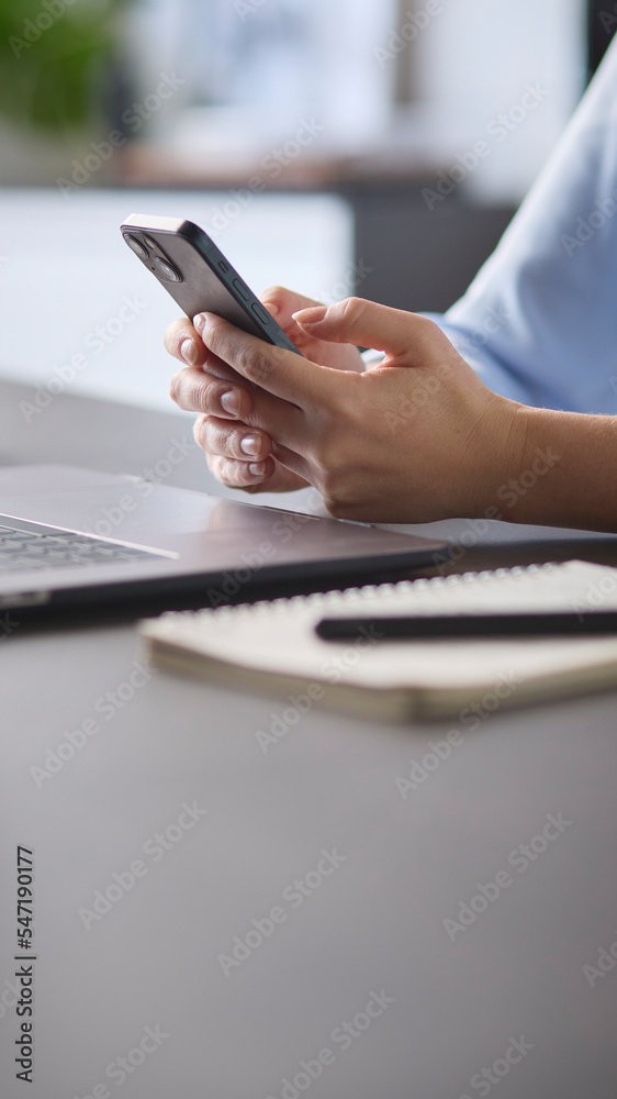 Fototapeta premium Close Up Of Woman Using Mobile Phone At Desk Using App Or Searching Social Media