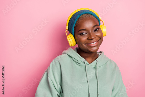 Portrait of good mood pretty fashionable girl wearing headphones over beanie isolated on pink color background