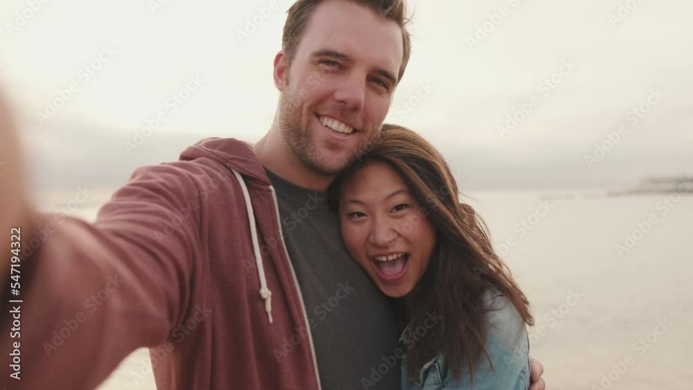 Couple in love hugging each other makes selfie while standing on the beach Couple in love hugging each other makes selfie while standing on the beach