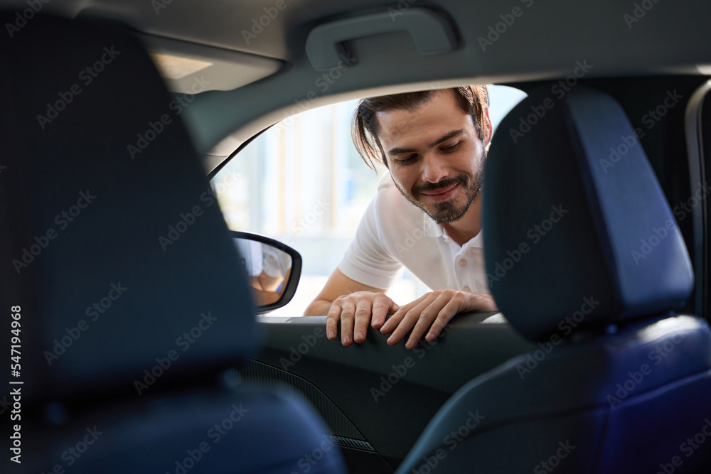 Pleased potential buyer is inspecting motor vehicle interior - obrazy, fototapety, plakaty 