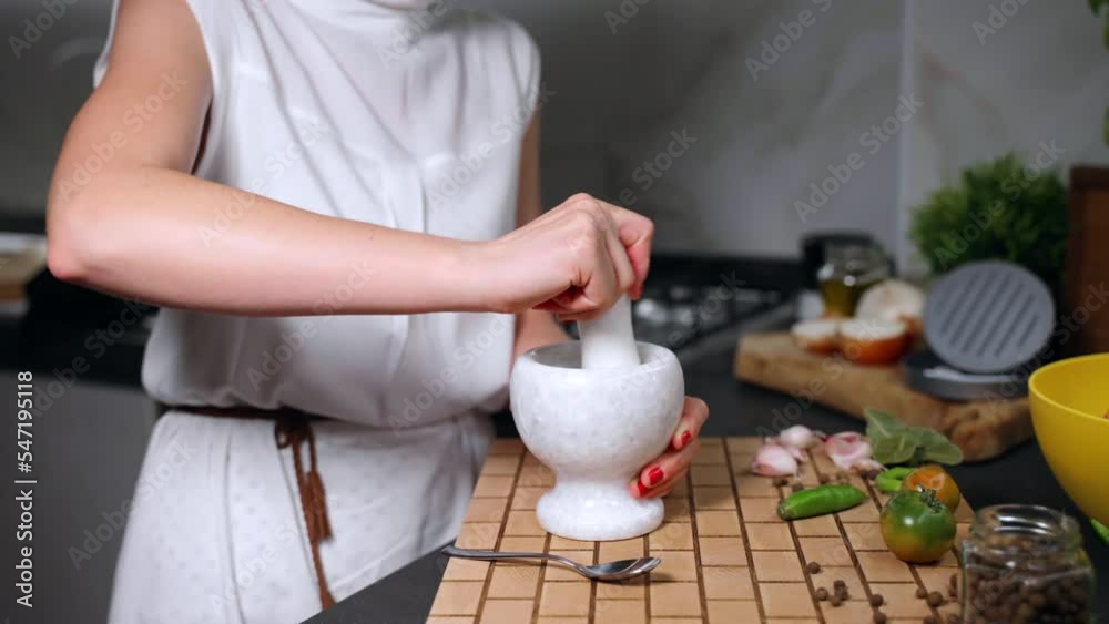 Stone grinding bowl on wooden board for crushing spices and herbs, woman mixing aroma flavours