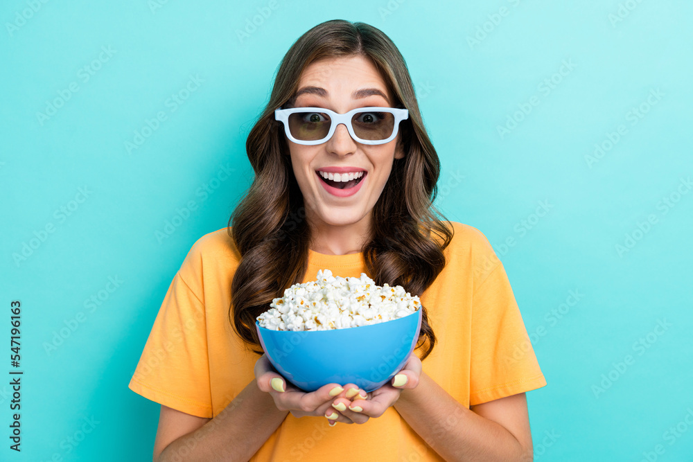 Photo of impressed excited lady wear yellow t-shirt eating pop corn watching 3d movie isolated turquoise color background