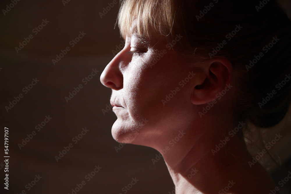Portrait of a middle-aged sad blonde woman in the room. Photoshoot in a dark key Portrait of a middle-aged sad blonde woman in the room. Photoshoot in a dark key