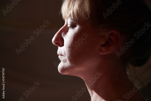 Portrait of a middle-aged sad blonde woman in the room. Photoshoot in a dark key