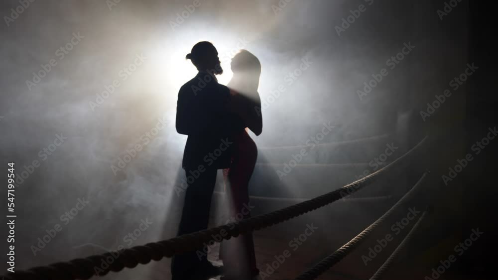 sexy woman with big breasts is seducing stylish bearded man on boxing ring, silhouette of lovers