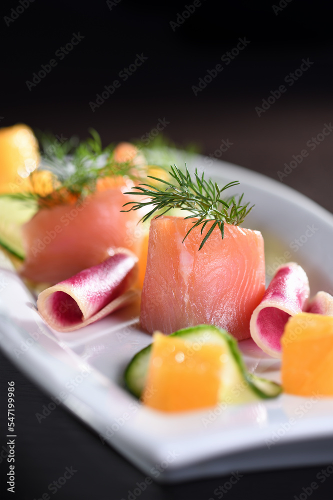 Buffet serving of pickled salmon slices with radish, cucumber and orange cubes Buffet serving of pickled salmon slices with radish, cucumber and orange cubes