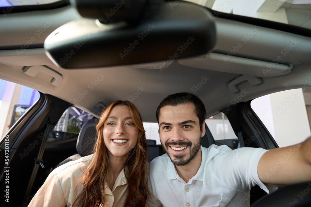 Happy couple taking selfies in new vehicle