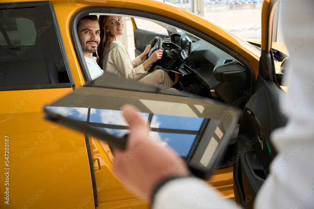 Naklejka premium Young couple choosing motor vehicle at dealership