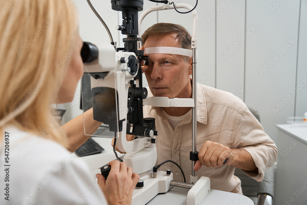 Physician examining the eyeball of patient in hospital Physician examining the eyeball of patient in hospital