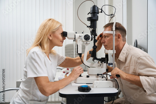 Physician examining the eyeball of patient in cabinet