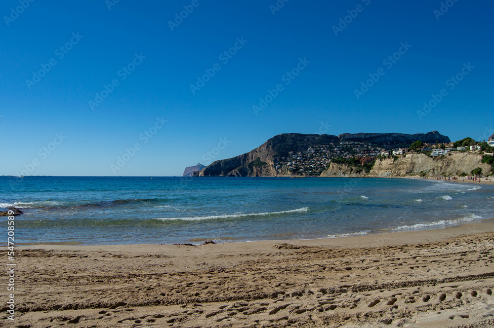 Playa de la costa blanca en el pueblo pequeño de Calpe en la provincia de Alicante con el mar Mediterráneo bajo un precioso cielo soleado 