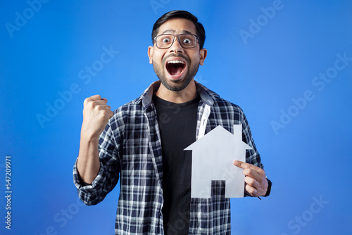 Happiness, home insurance, smiley face. Student with big smile holding house model.