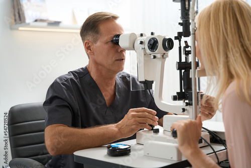 Physician is examining the eyeball of lady