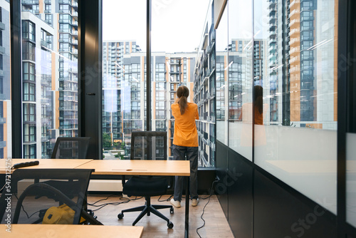 Employee of the cleaning service is resting and looking out the window