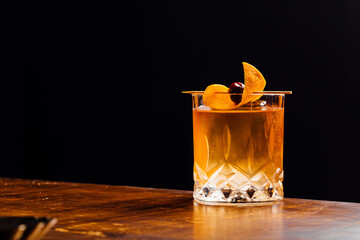 old fashioned cocktail on a wooden table and black background
