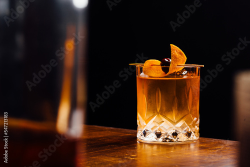 old fashioned cocktail glass between bottles in a bar