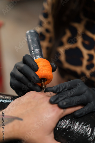 Woman tattoo artist makes a tattoo to a man on his arm, tattoo studio