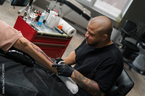 Close-up - the process of tattooing a woman on her leg. Male tattoo artist making a tattoo