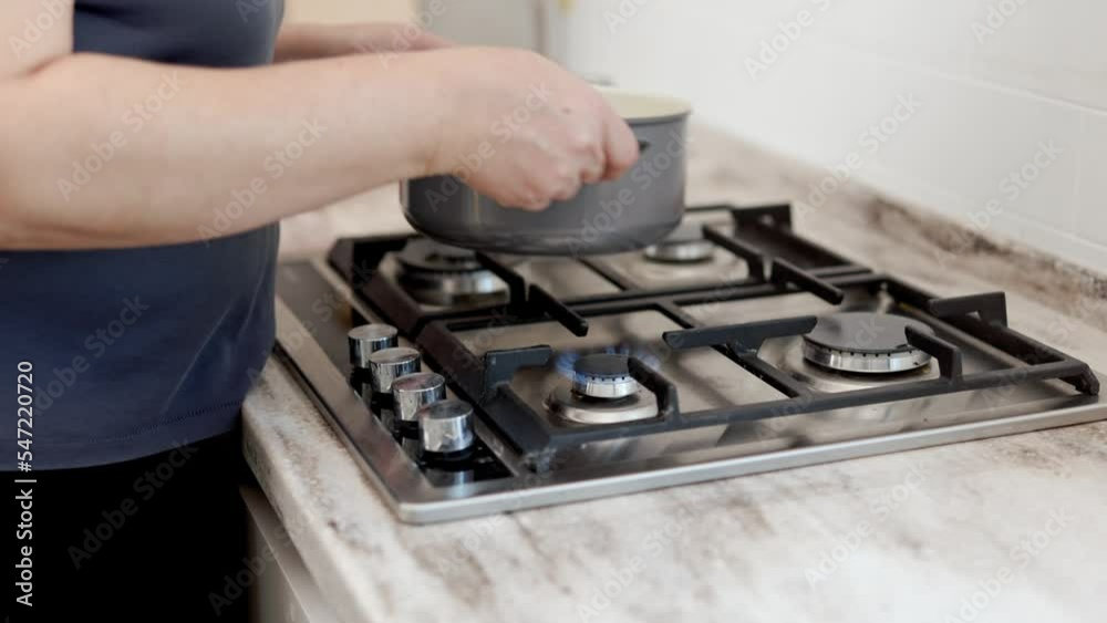 The woman turns on the gas and puts a pot of water on the gas stove. The woman turns on the gas and puts a pot of water on the gas stove.