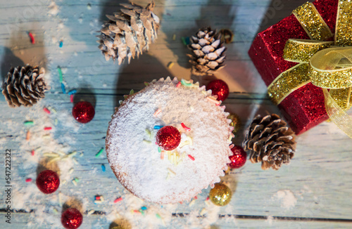 Muffin, cake with cranberry and nuts. On the background of cones and present box. Christmas decoration. Top view. 