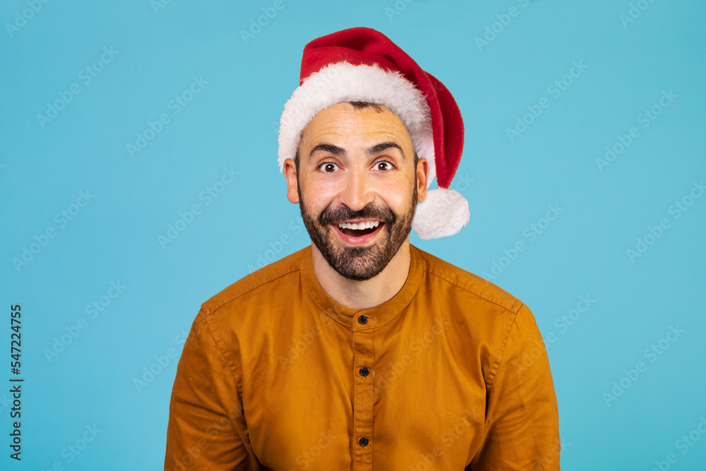 Portrait of positively excited shocked amazed man in christmas hat seeing big sale on blue background Portrait of positively excited shocked amazed man in christmas hat seeing big sale on blue background