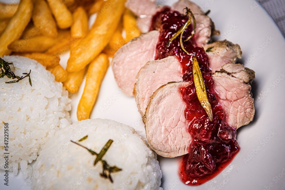 Baked pork tenderloin with cranberry sauce, rice and fries