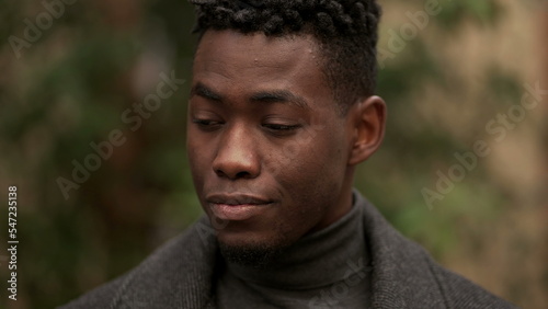 Handsome young black man standing outdoors thinking