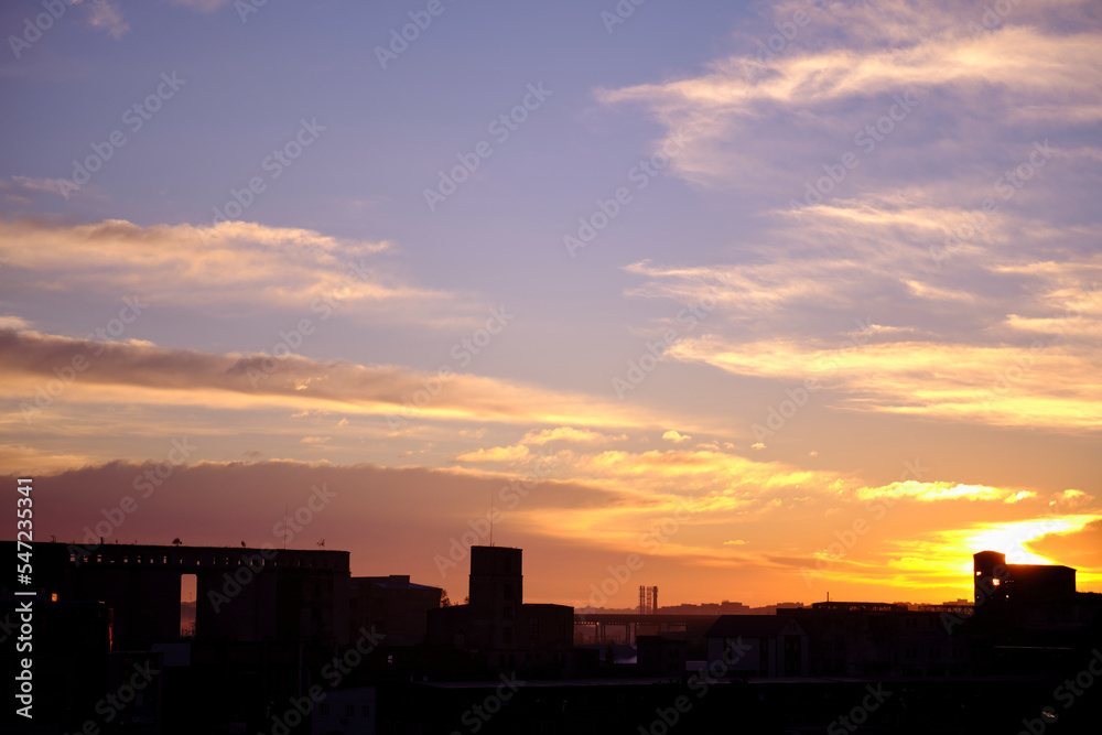 Silhouette of a broken forgotten factory on the background of sunset or sunrise