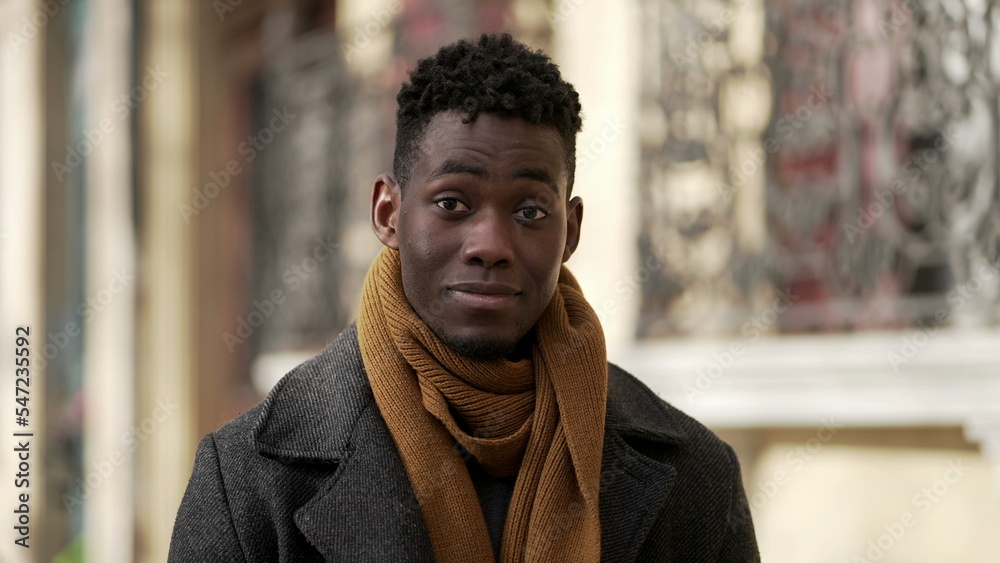 Friendly black african man portrait smiling at camera standing outdoors in urban city wearing scar furing cold season Friendly black african man portrait smiling at camera standing outdoors in urban city wearing scar furing cold season