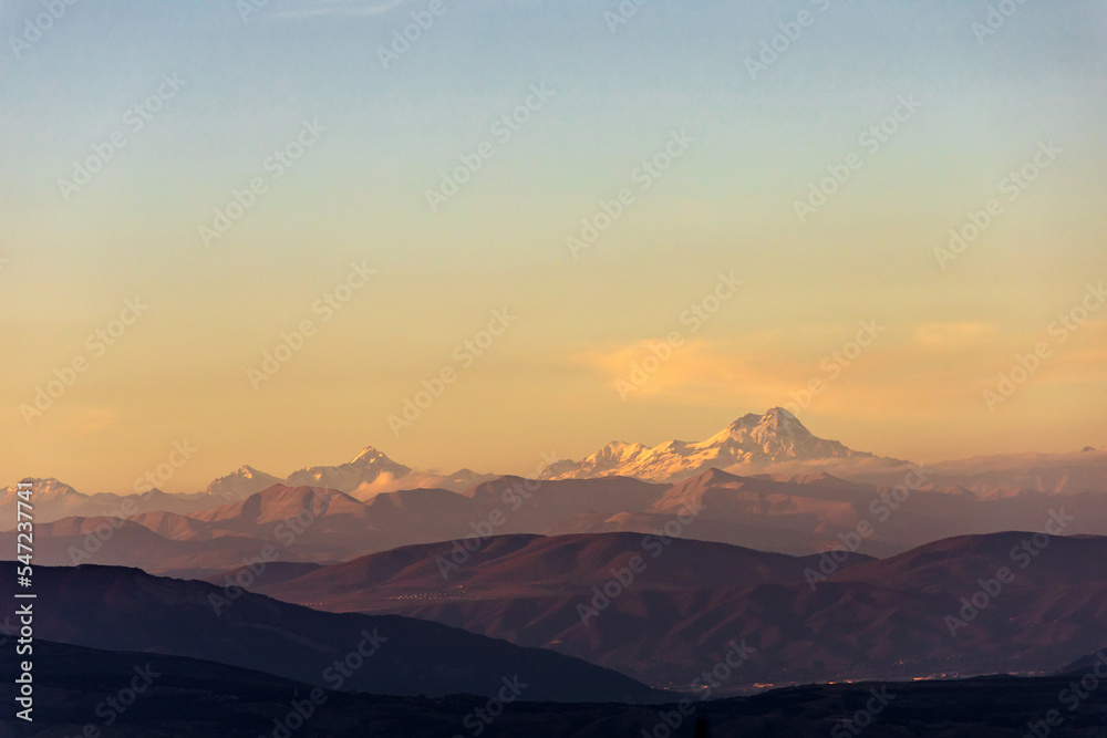 landscape with the peak of Mount Kazbek on the horizon in the rays of the setting sun