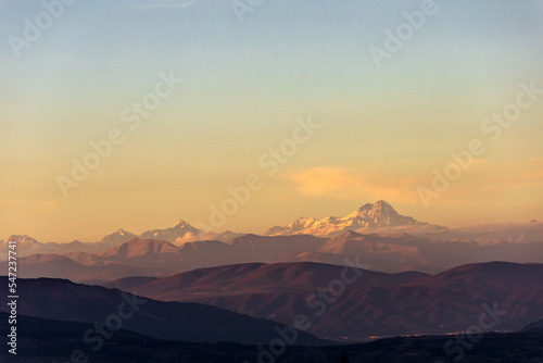 landscape with the peak of Mount Kazbek on the horizon in the rays of the setting sun photo