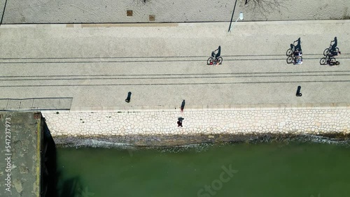 Aerial drone view of people bicycling next to the river in the city of Lisbon, Portugal. Digital nomads. World’s Leading Seaside Metropolitan Destination. Daily life and lifestyle. 