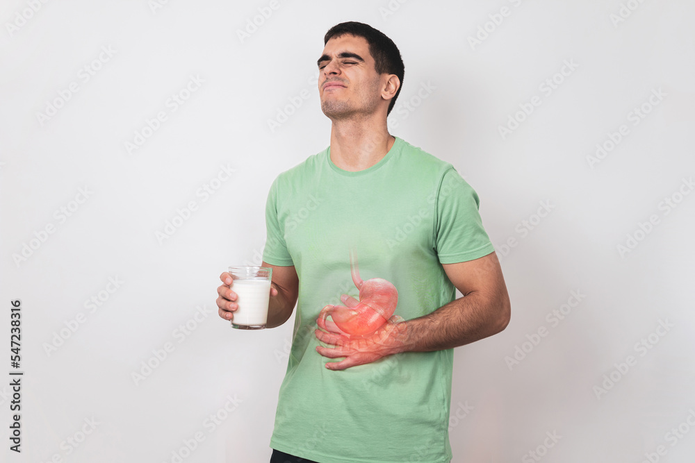 Lactose intolerance. A young man holds a glass of milk in his hand and