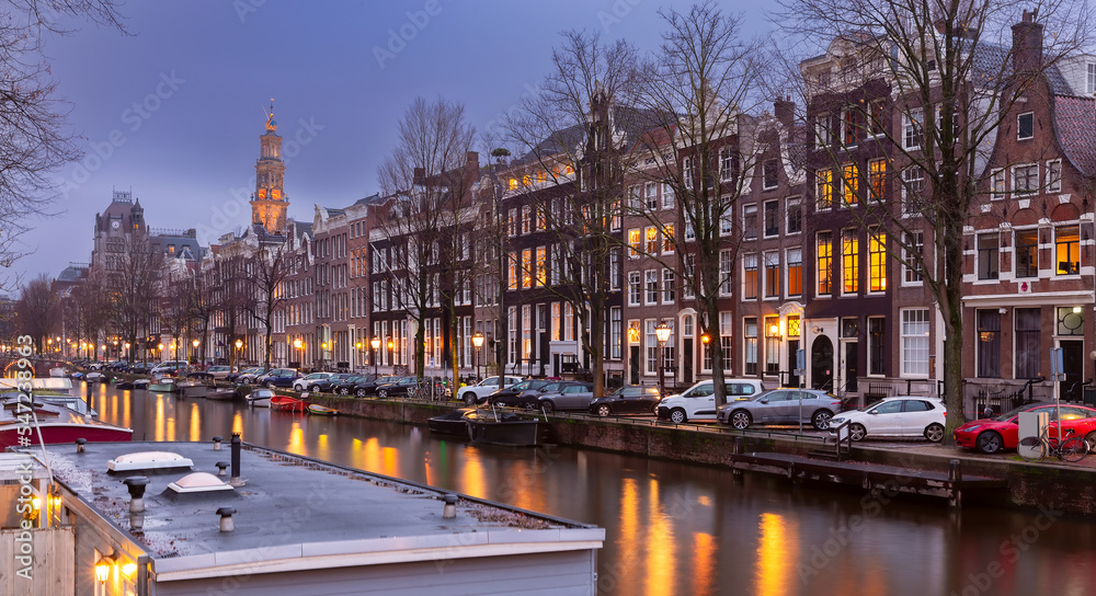 Beautiful old houses on the city waterfront of Amsterdam at sunset.