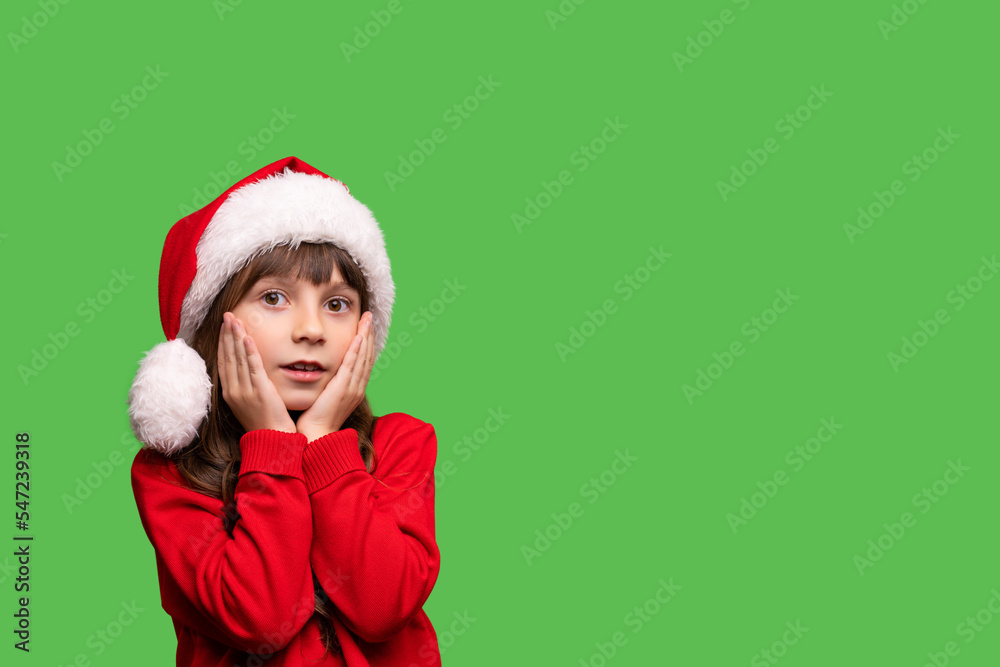 Merry Christmas and New Year. Portrait of a surprised girl in a red Santa hat waiting for Christmas gifts. Merry Christmas and New Year. Portrait of a surprised girl in a red Santa hat waiting for Christmas gifts.