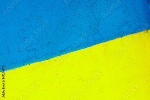 The flag of Ukraine on the fence. The surface of the concrete fence is painted yellow and blue. Texture surface for text.