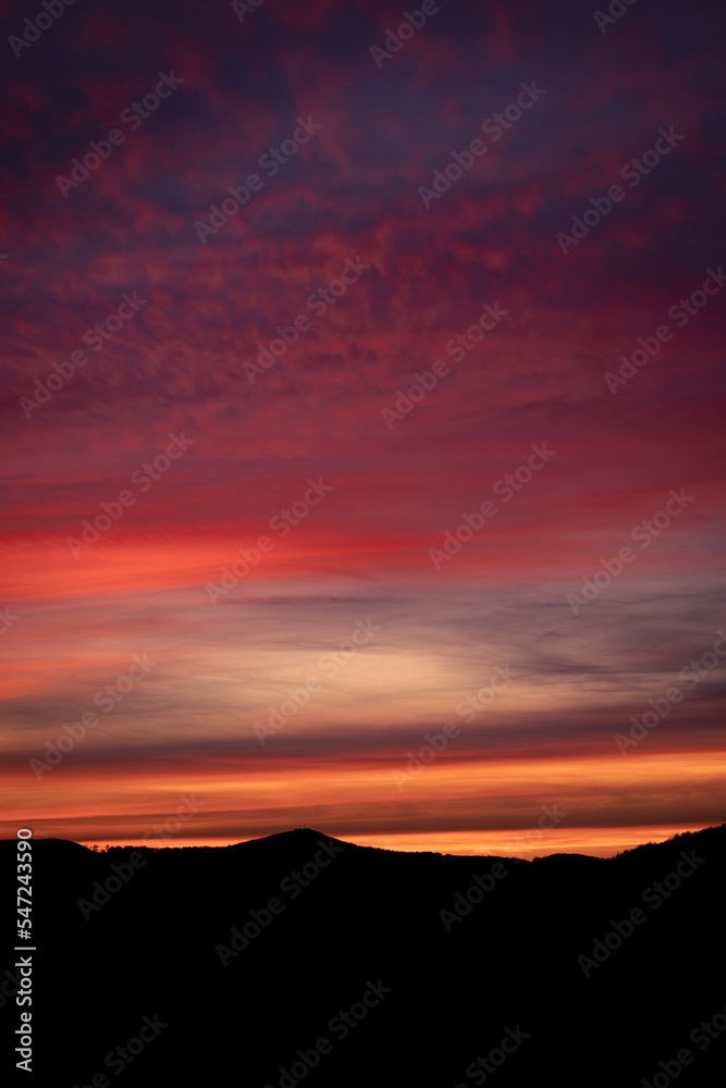 Silhouettes of mountains, red, colorful winter sunset sky in Germany, Europe 