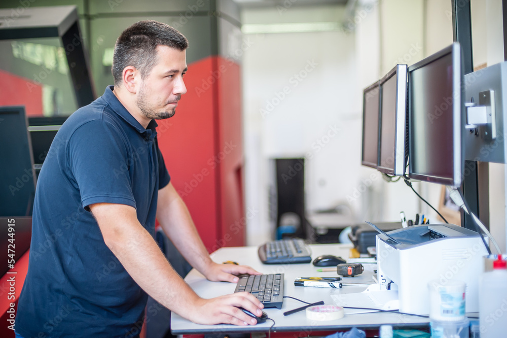 Professional worker with modern big offset printing machine in print house. Printing industry concept background.