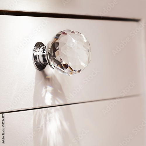 Close-up of acrylic drawer pulls with selective lighting over them. Part of a white bed table