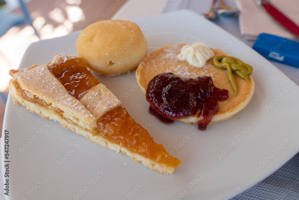 Delicious pancake with strawberry jam bun and apricot tart on white plate Delicious pancake with strawberry jam bun and apricot tart on white plate