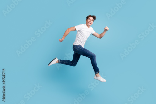Side view of joyous man in sneakers denim outfit running hurrying for discounts indoor studio shot isolated © Tetiana